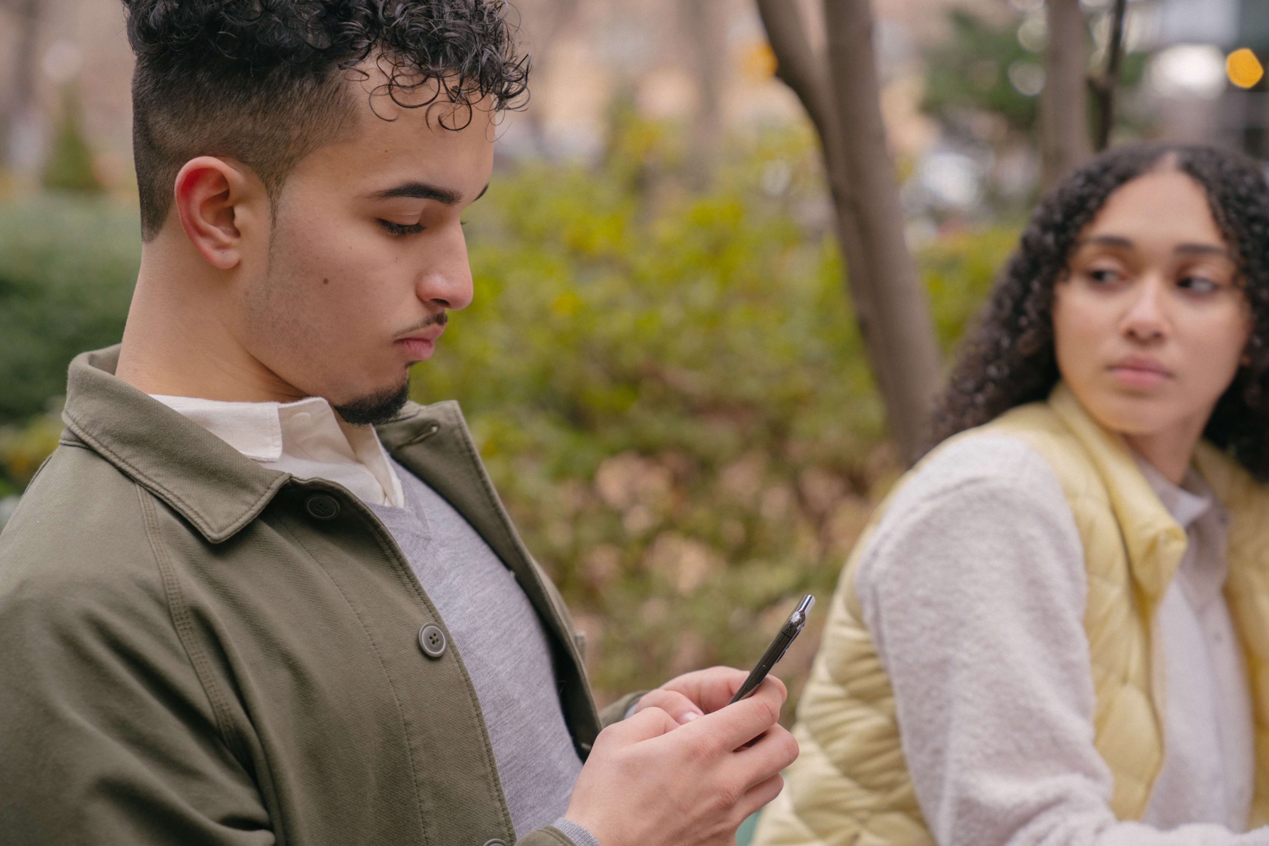 A lady looking jealously at boyfriend while texting on phone